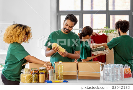 happy volunteers packing food and clothes in boxes happy volunteers packing food and clothes in boxes 88942183