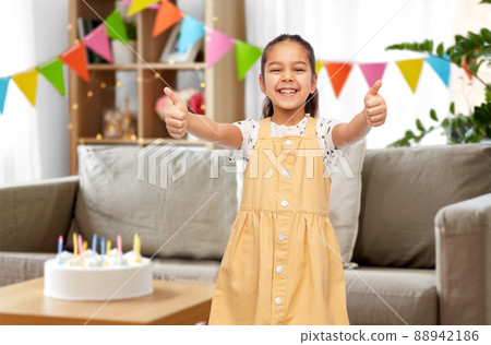 girl showing thumbs up at birthday party at home girl showing thumbs up at birthday party at home 88942186