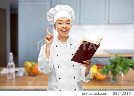 female chef with cook book pointing finger up 88942217