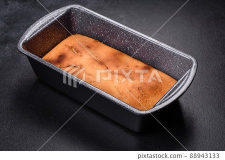 Baked rectangular cupcake with raisins and chocolate on a dark concrete background Baked rectangular cupcake with raisins and chocolate on a dark concrete background 88943133