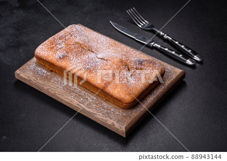 Baked rectangular cupcake with raisins and chocolate on a dark concrete background Baked rectangular cupcake with raisins and chocolate on a dark concrete background 88943144