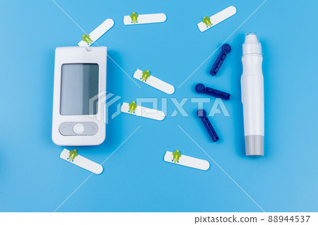 Digital glucometer, lancet pen, disposable needles and test strips on pastel blue background. Top view. Diabetes concept 88944537