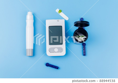 Digital glucometer, lancet pen, disposable needles and test strips on pastel blue background. Top view. Diabetes concept 88944538