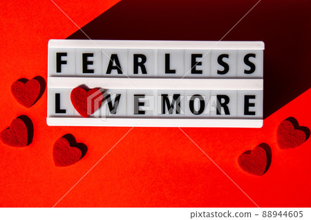 Lightbox with text FEAR LESS LOVE MORE. Motivational Words Quotes Concept with red hearts. Colorful red background. Minimalistic creative concept. 88944605