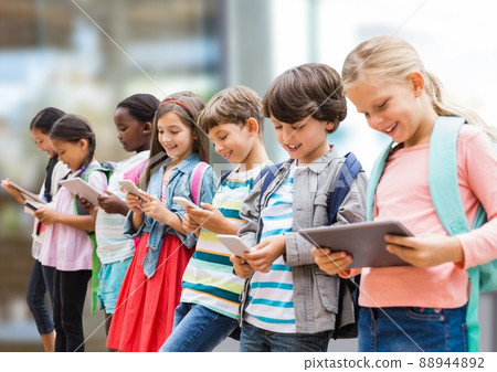 Group of diverse school students using electronic devices against blurred background 88944892