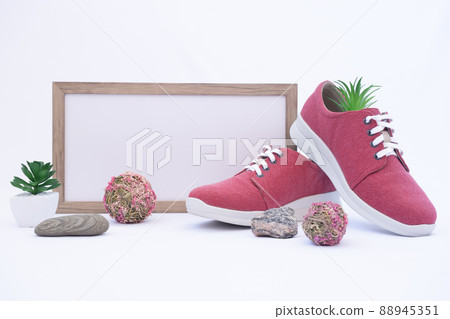 A pair of burgundy shoes in a shop window. There is a frame with space for text. The concept of environmentally friendly shoes. Shoes made from recycled materials. Nature design elements: grass A pair of burgundy shoes in a shop window. There is a frame with space for text. The concept of environmentally friendly shoes. Shoes made from recycled materials. Nature design elements: grass 88945351
