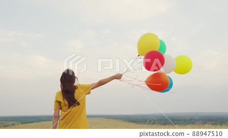 young girl with air beautiful balloons against blue sky. walk child nature. festive mood teenager. happy carefree. hold gel balls hand. blue green red orange yellow colors. fun one person journey. young girl with air beautiful balloons against blue sky. walk child nature. festive mood teenager. happy carefree. hold gel balls hand. blue green red orange yellow colors. fun one person journey. 88947510