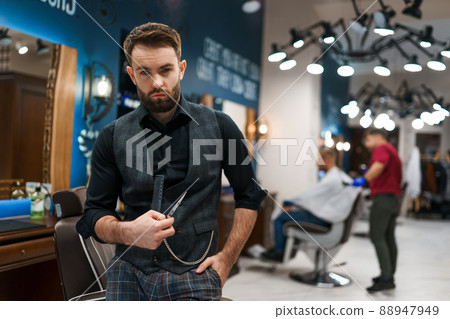 Brutal barber master with scissors and a comb in his hands Brutal barber master with scissors and a comb in his hands 88947949