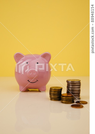 Piggy bank with stack of coins on yellow background Piggy bank with stack of coins on yellow background 88948154