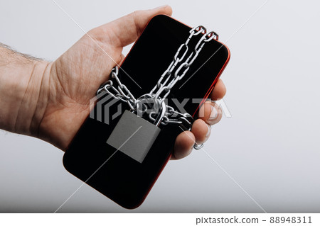 Modern smartphone with chain locked in man's hand. Information security concept 88948311