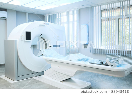 Modern large computer tomography machine with table covered with disposable sheet in hospital room 88948418