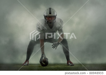 American football player posing with ball on black background Stock Photo  by master1305