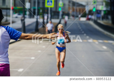 volunteer gives water in glass to female athlete running marathon volunteer gives water in glass to female athlete running marathon 88953122