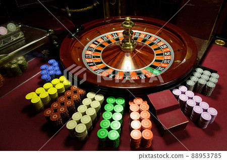 There is a red table with roulette chips in the casino 88953785