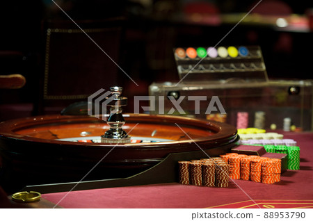 There is a red table with roulette chips in the casino 88953790