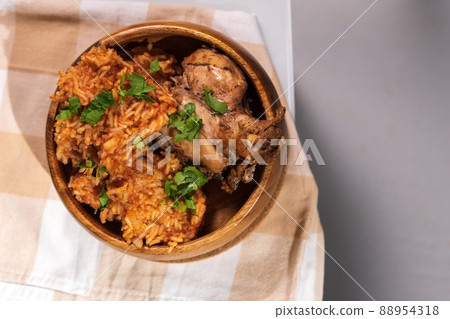 Tasty Nigerian Jollof Rice served and decorated with some green spices and chicken 88954318
