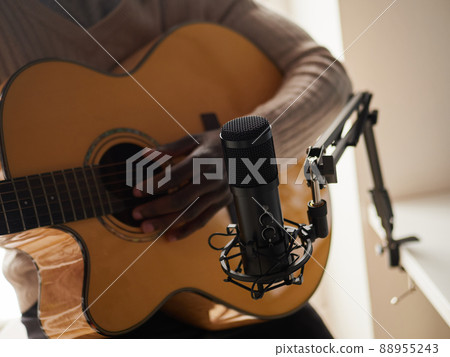 Young man is singing and playing guitar while making an audio recording at home Young man is singing and playing guitar while making an audio recording at home 88955243