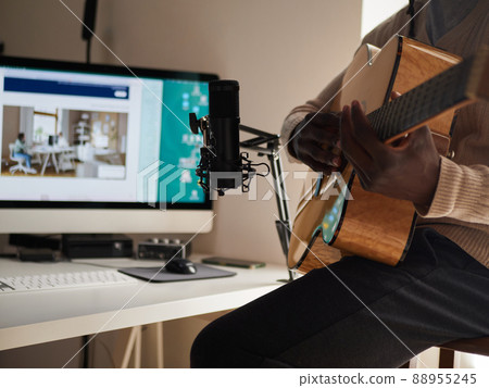 Young man is singing and playing guitar while making an audio recording at home Young man is singing and playing guitar while making an audio recording at home 88955245
