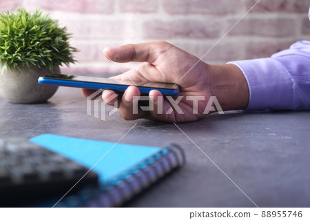 side view of young man hand using smart phone on table side view of young man hand using smart phone on table 88955746