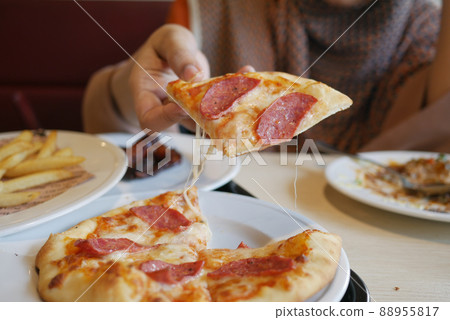 women hand picking slice of pizza from a plate women hand picking slice of pizza from a plate 88955817