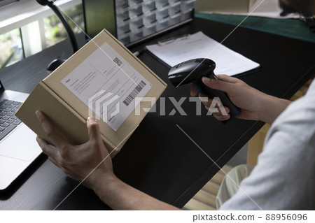 Male seller online store worker holding scanner scanning parcel bar code packing Male seller online store worker holding scanner scanning parcel bar code packing 88956096