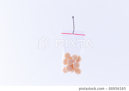Colored Pills or Tablets Hanging in Small Ziplock Bag on a Fishing Hook Colored Pills or Tablets Hanging in Small Ziplock Bag on a Fishing Hook 88956165