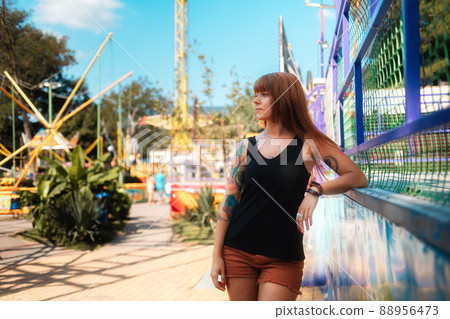Beautiful young woman with tattoos looking to the left and posing in an amusement park. The concept of freedom, loneliness and psychology 88956473