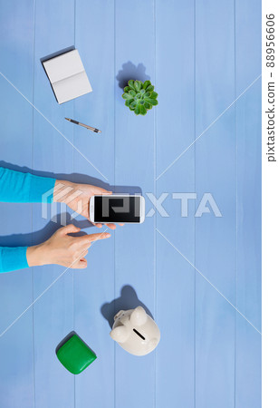 Person using smartphone with piggy bank Person using smartphone with piggy bank 88956606
