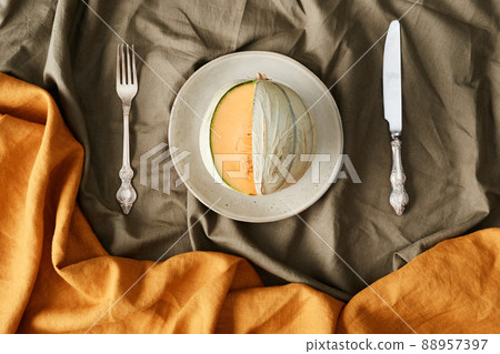 Directly above view of delicious watermelon on plate and served silverwate on wrinkled tablecloth, autumn colors 88957397
