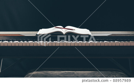 Open notepad on piano keys in the dark, copy space. 88957989