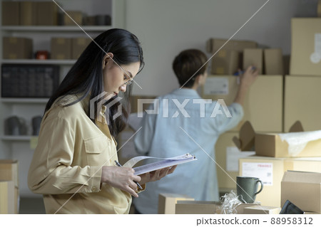 Asian woman online seller confirming orders from customer on the papers 88958312