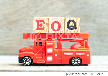 Fire ladder truck hold letter block in word EOQ (Abbreviation of Economic order quantity) on wood background 88959440