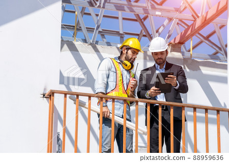 Architect and developer with blueprints discussing architect project at construction site. 88959636
