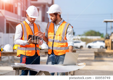 Engineer and architect discussing building plan at construction site. 88959749
