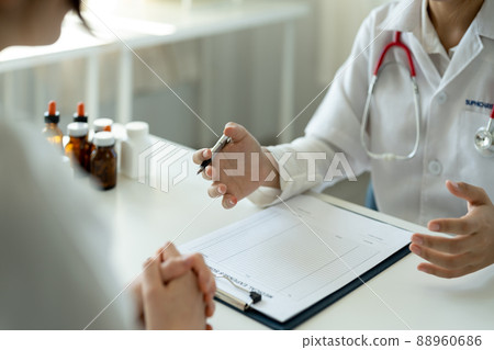 Asian female doctor in white medical uniform consult female patient in private hospital. woman therapist speak talk with woman client on consultation in clinic 88960686