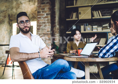 Portrait of millennial Turkish IT professional in eyeglasses holding smartphone gadget Portrait of millennial Turkish IT professional in eyeglasses holding smartphone gadget 88960934