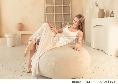 young girl in white dress lies on pouffe young girl in white dress lies on pouffe 88961453