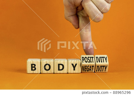 Body positivity or negativity symbol. Psychologist turns cubes, changes words body negativity to body positivity. Orange background, copy space. Psychological, body positive or negative concept. Body positivity or negativity symbol. Psychologist turns cubes, changes words body negativity to body positivity. Orange background, copy space. Psychological, body positive or negative concept. 88965296