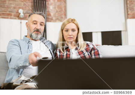 Married couple sitting on couch and watching film on laptop 88966369