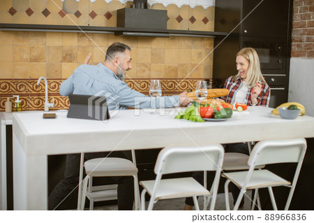 Couple using baguettes for playful fight on bright kitchen 88966836