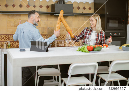 Couple having fun on kitchen while fighting with baguettes 88966837