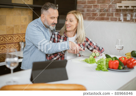 Mature loving couple cooking and using tablet on kitchen 88966846