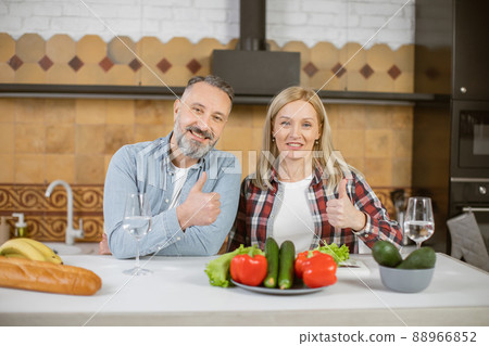 Portrait of mature couple posing in embrace on kitchen Portrait of mature couple posing in embrace on kitchen 88966852