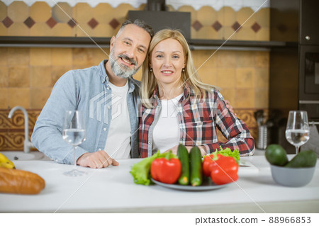 Portrait of mature couple posing in embrace on kitchen 88966853