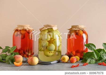 Three canned apple and cherry compote in large glass jars on gray table. 88967078