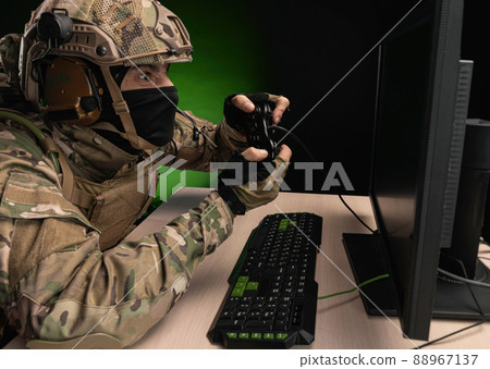 a military soldier at a computer is conducting a cyber war a military soldier at a computer is conducting a cyber war 88967137
