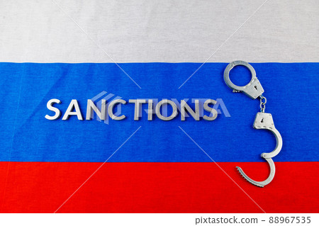 the word sanctions laid with silver metal letters on russian tricolor flag near handcuffs in directly above view the word sanctions laid with silver metal letters on russian tricolor flag near handcuffs in directly above view 88967535