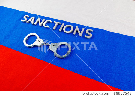 the word sanctions laid with silver metal letters on russian tricolor flag near handcuffs in directly above view the word sanctions laid with silver metal letters on russian tricolor flag near handcuffs in directly above view 88967545