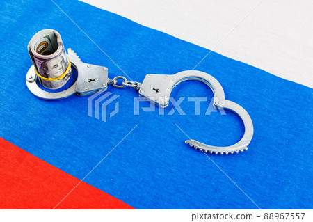 roll of us dollar banknotes in a handcuffs on flat full-frame russian flag 88967557