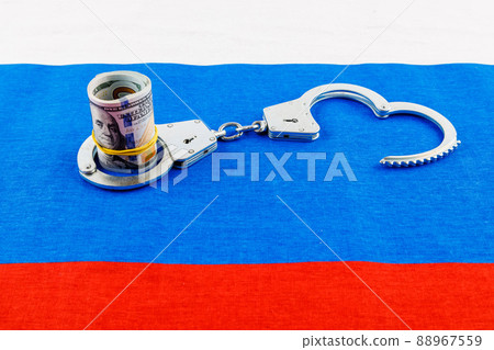 roll of us dollar banknotes in a handcuffs on flat full-frame russian flag 88967559